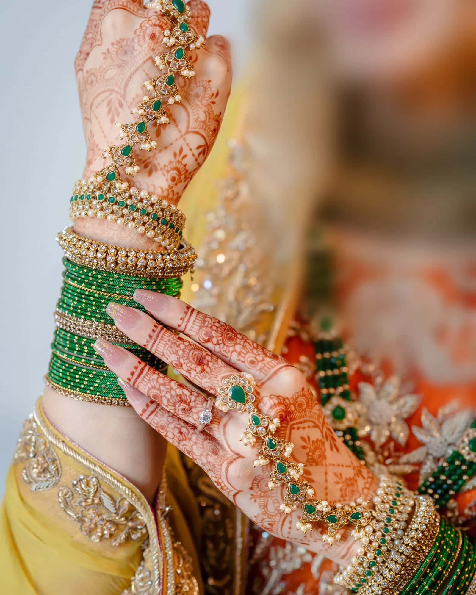 Hennaed hands with green bangles and rings