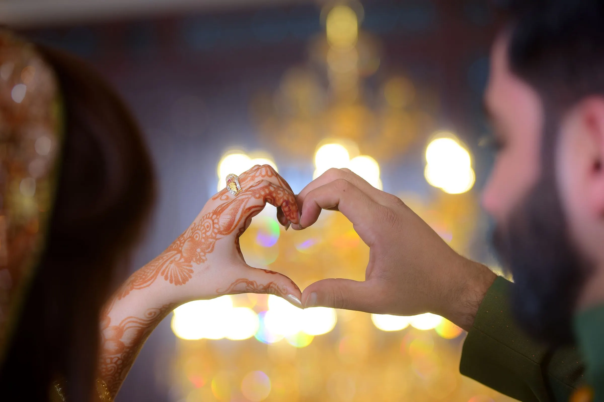 A bride's hennaed hands with rings and red bangles