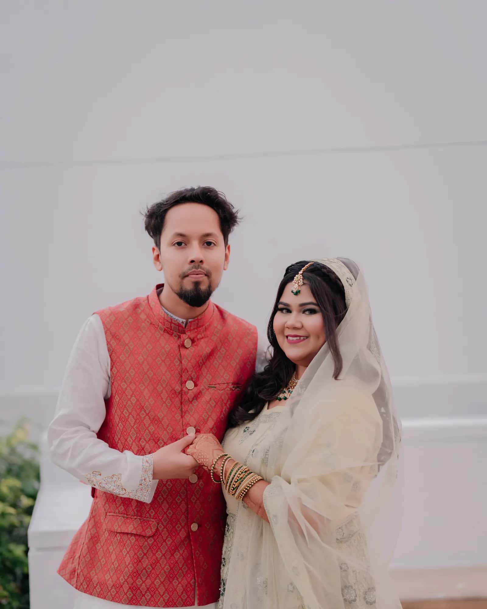 A couple in wedding clothes sitting together on a small bridge