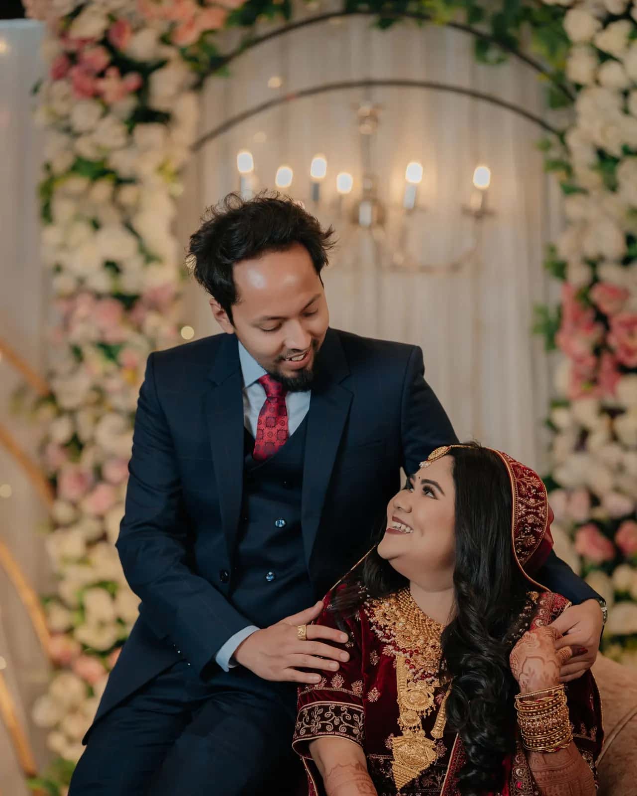 A laughing bride sitting between her mother and father