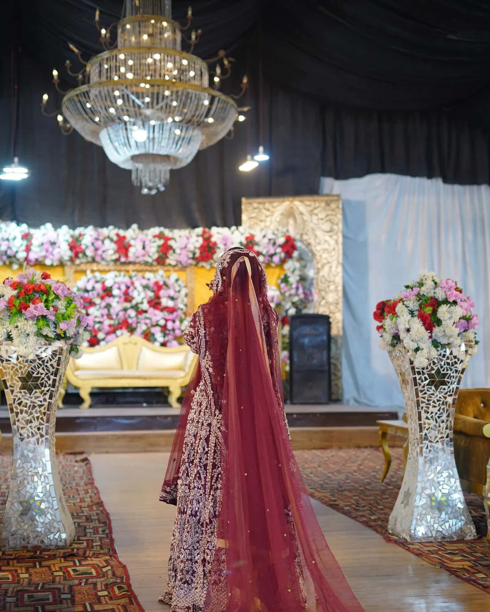 A bride and groom walking through a white arched corridor