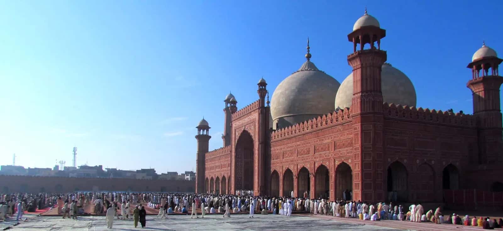 Eid prayers in the courtyard of the Badshahi Mosque in Lahore, the red sandstone domes above the rows of worshippers