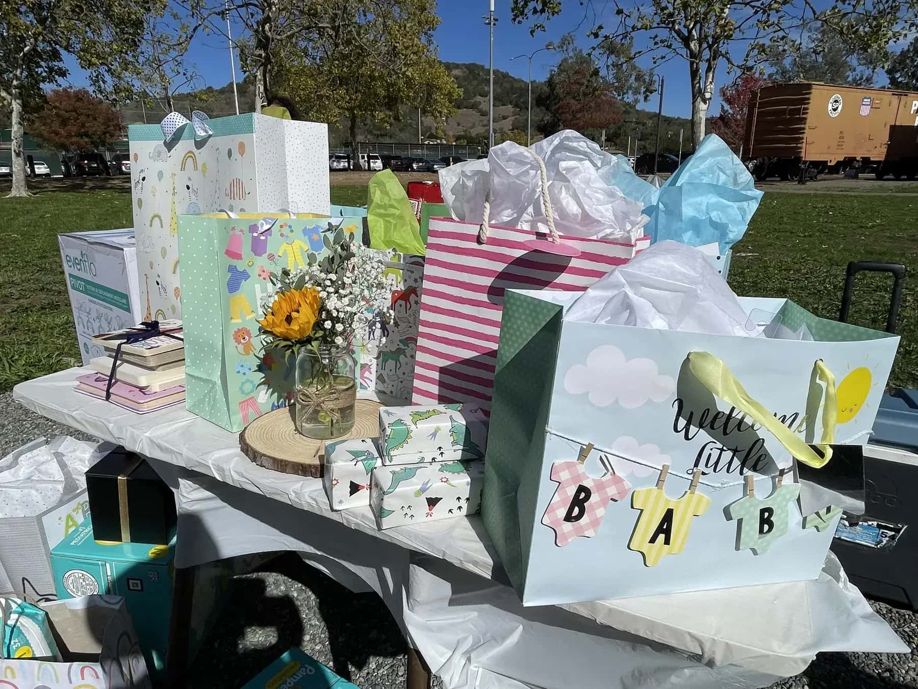 A table of wrapped baby shower gifts in pastel bags and tissue paper