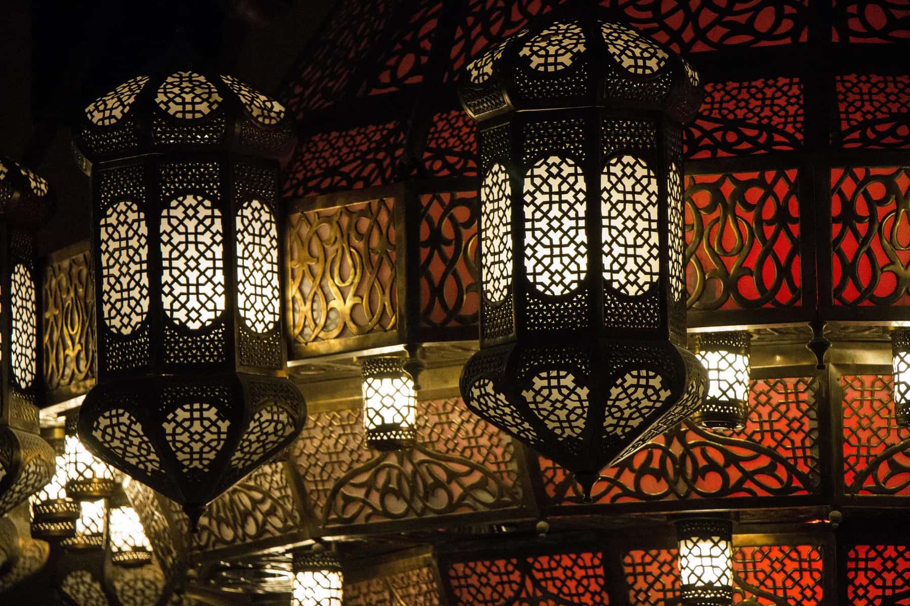 Carved metal lanterns glowing orange and gold in the dark