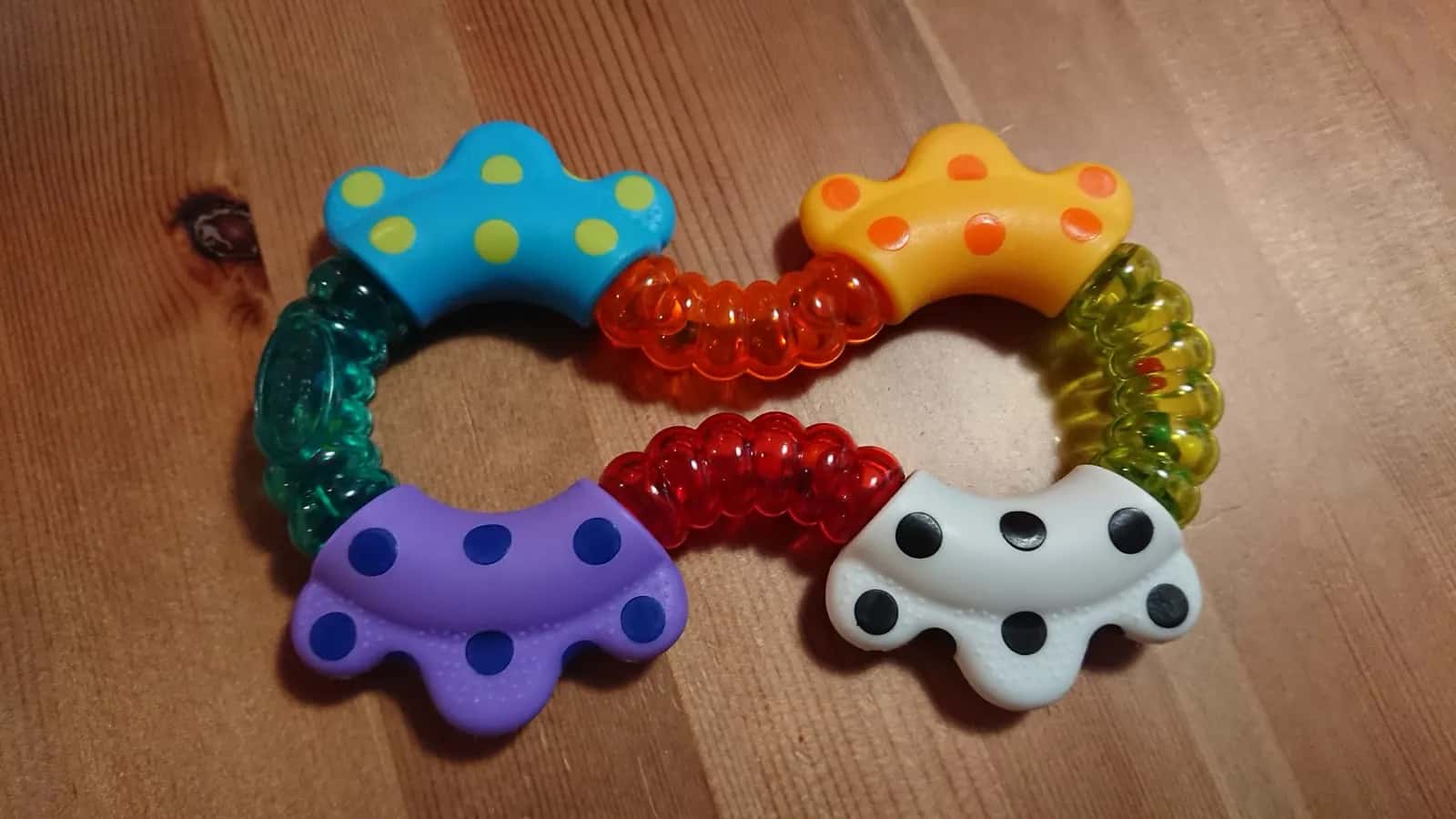 A colourful baby rattle with polka-dot petals on a wooden table