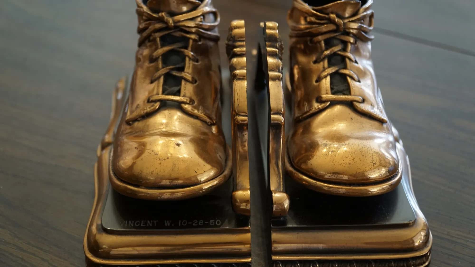 A pair of baby's first shoes, laced and bronzed, mounted on a stand