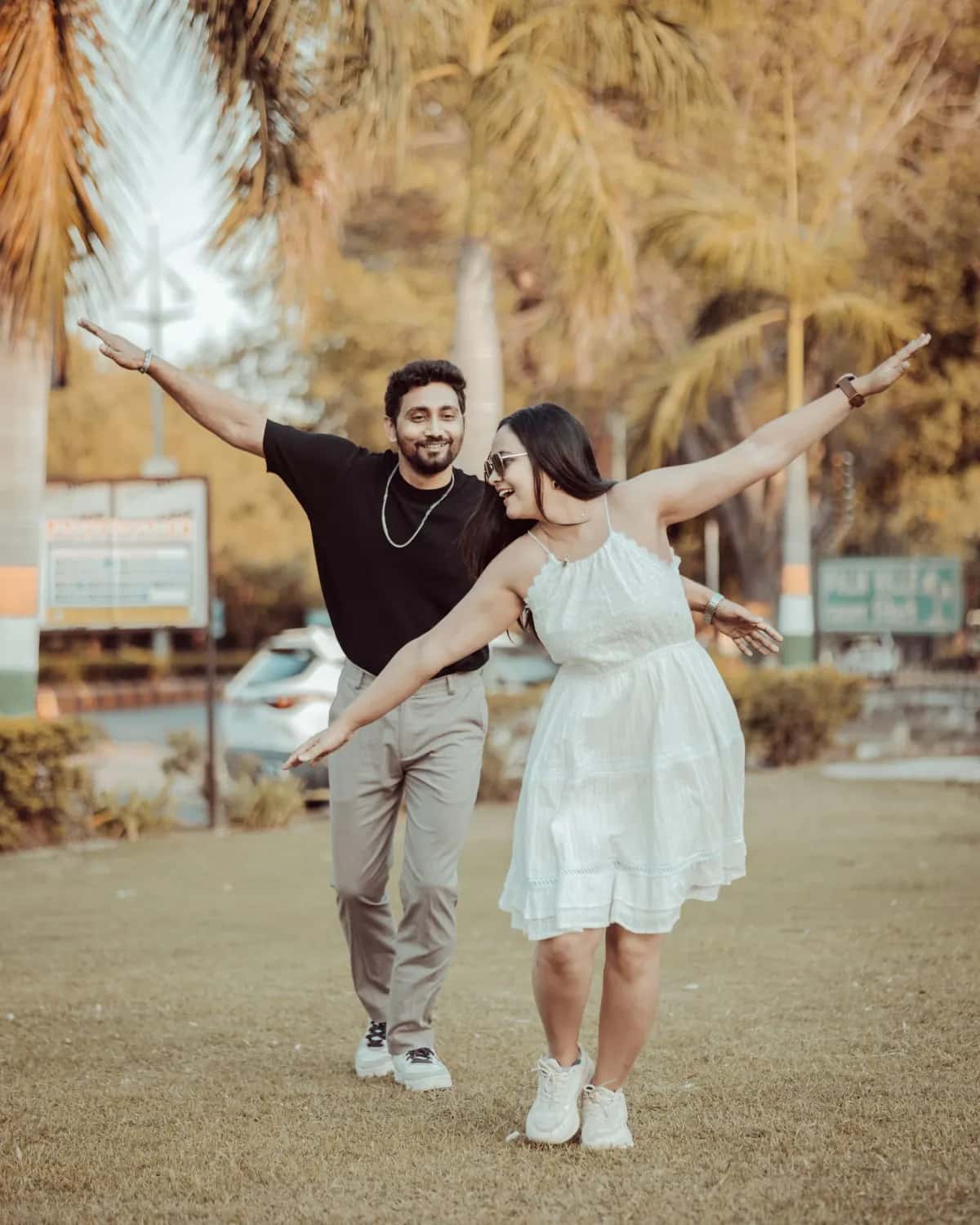 The two of them throwing their arms wide in a park