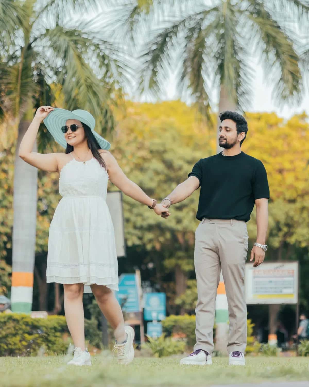 The couple holding hands under palm trees