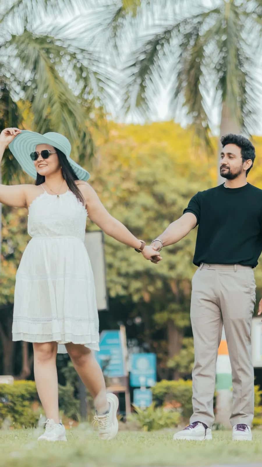 The couple holding hands under palm trees