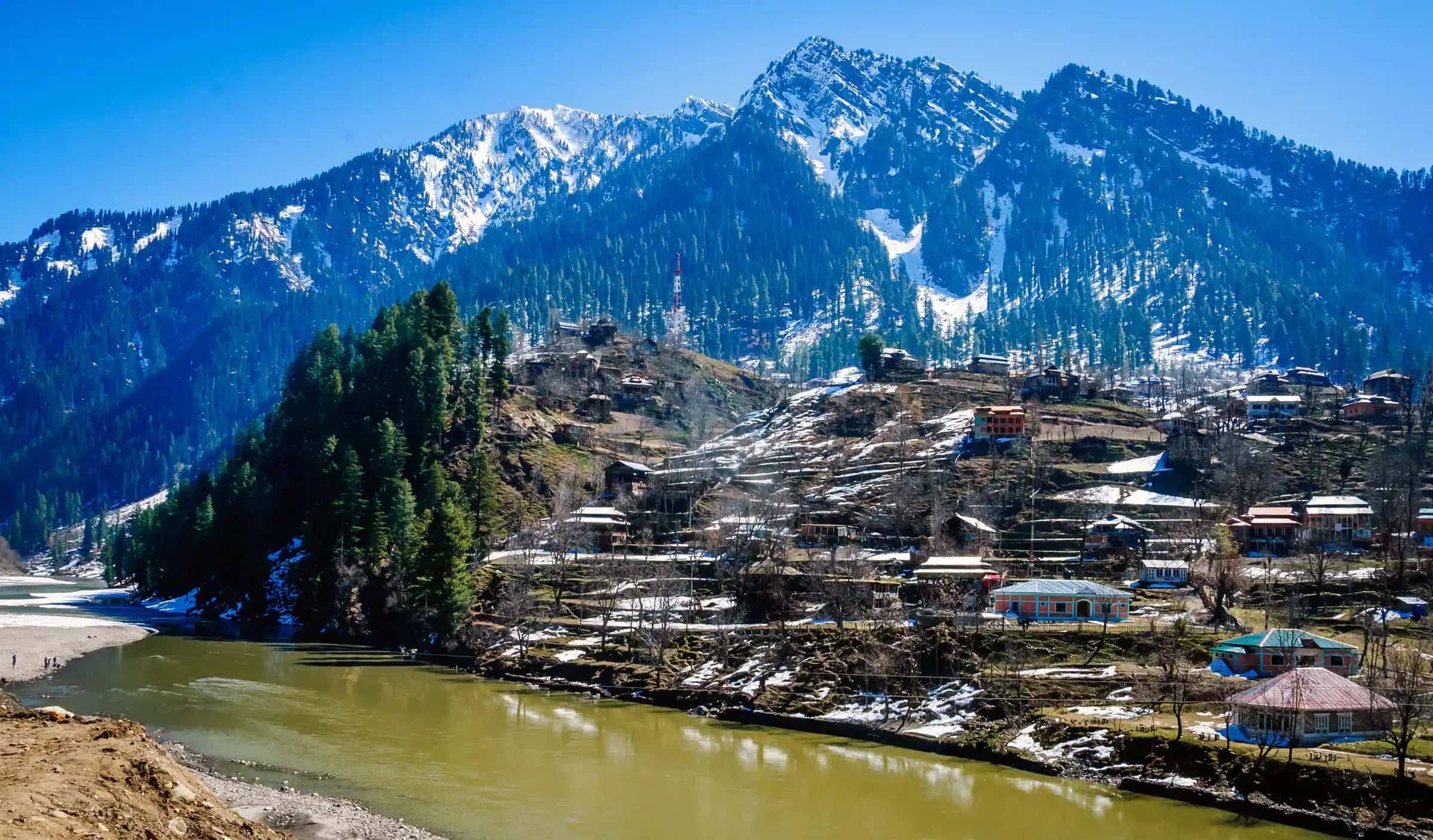 The rooftops of Sharda under snow, the river beside them and white ridges behind
