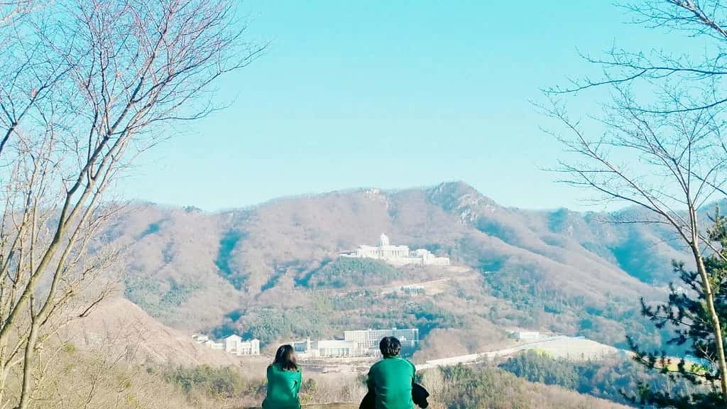 Two people sitting at a lookout, looking out over hazy hills