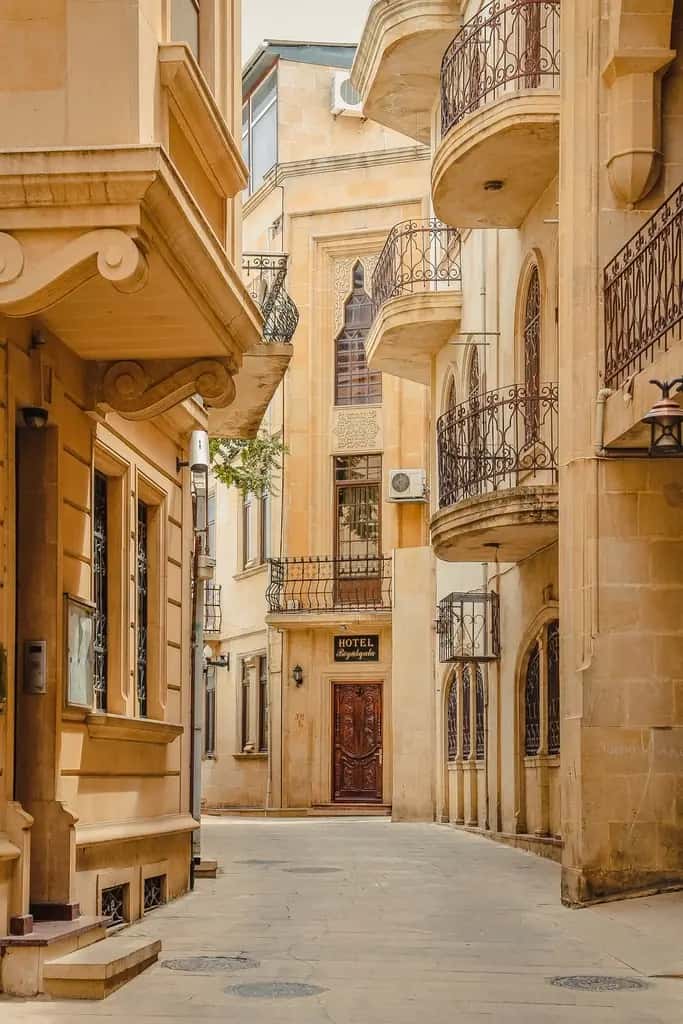 A narrow golden street of stone houses and iron balconies in old Baku
