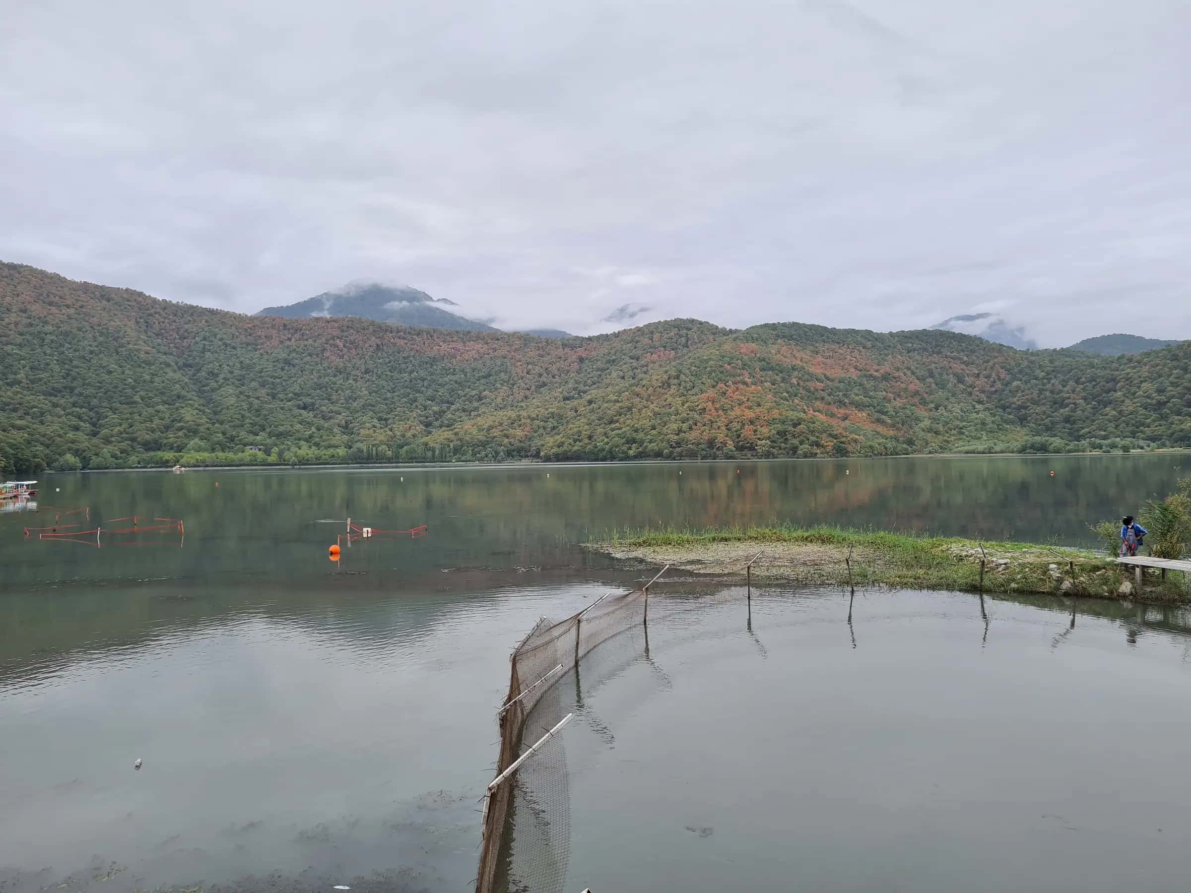 Nohur lake near Gabala below forested hills touched with autumn colour, a fishing net in the water