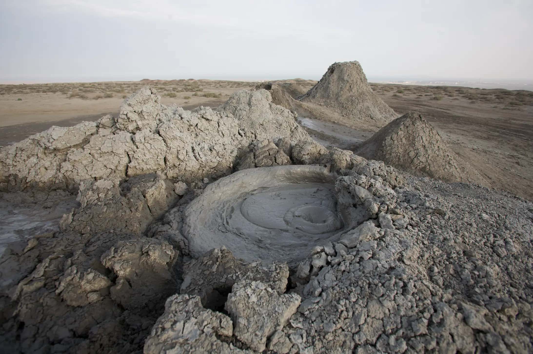 A grey mud volcano bubbling in the desert at Gobustan