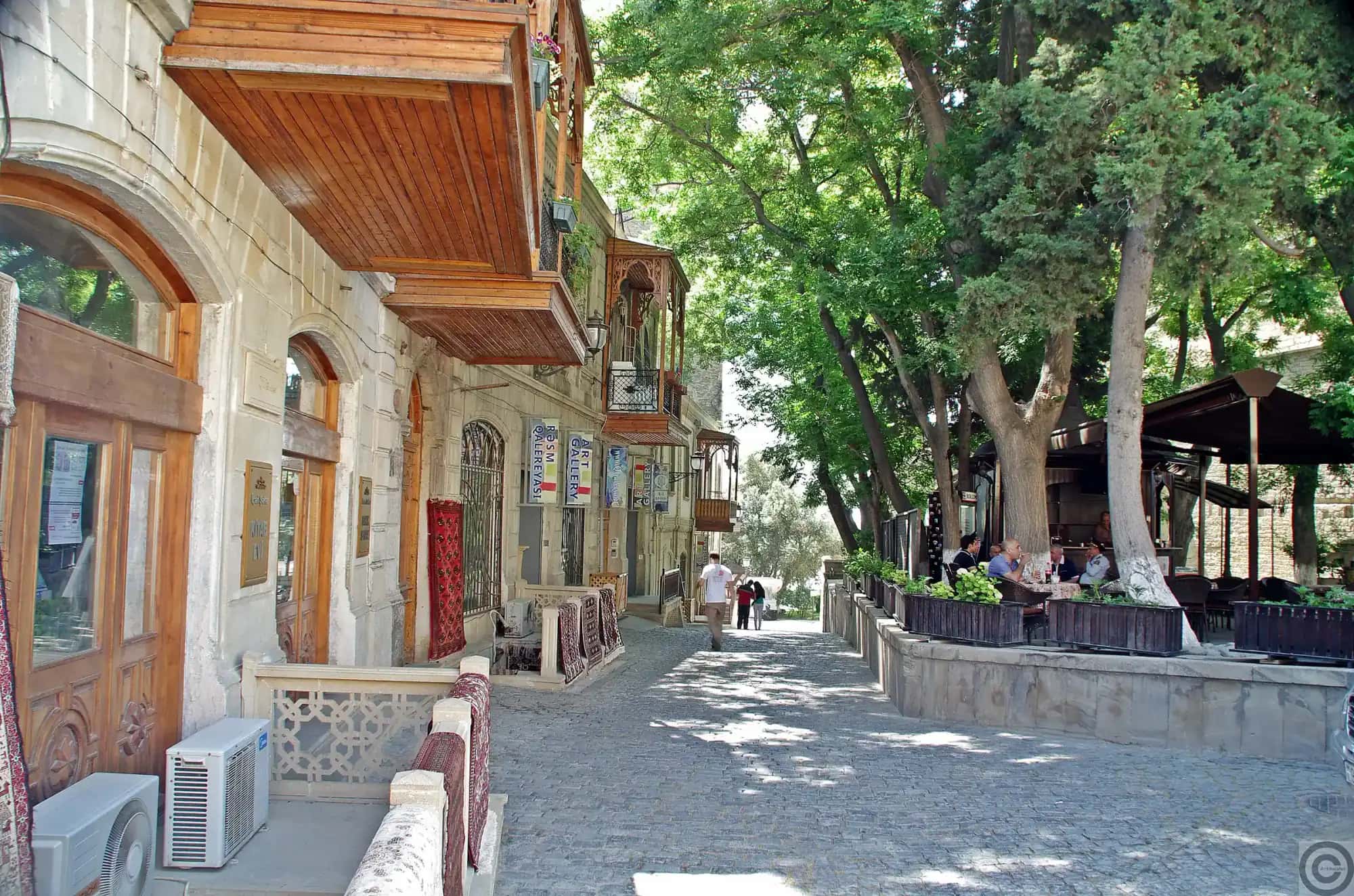 A quiet stone street inside the walls of Baku's old city, shaded by plane trees