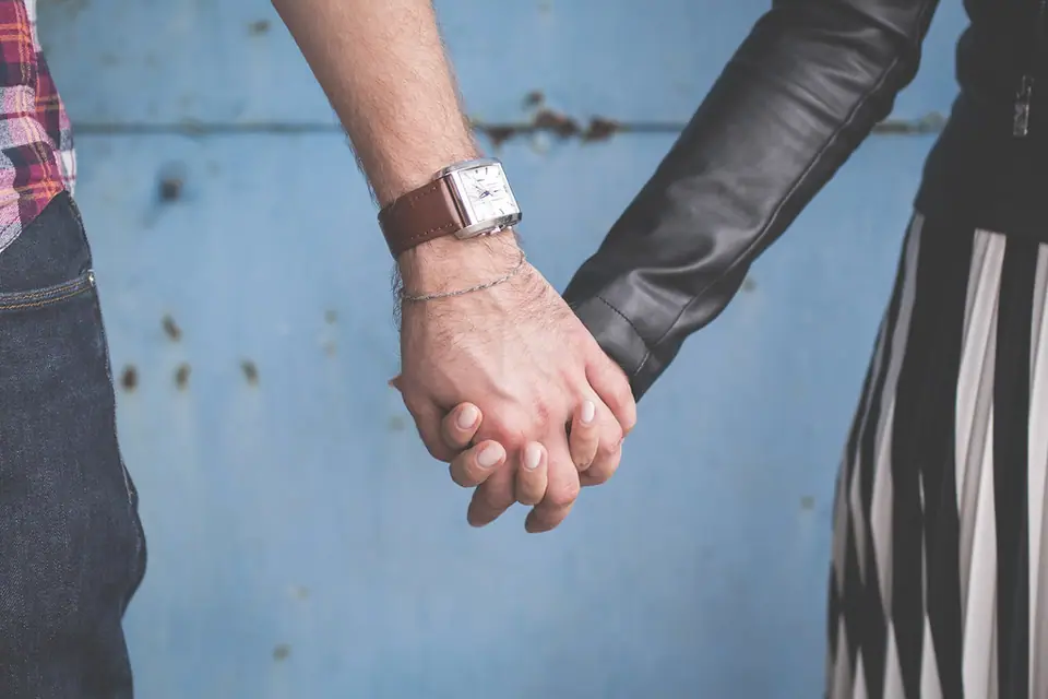 Two hands held against a blue wall, his watch on his wrist