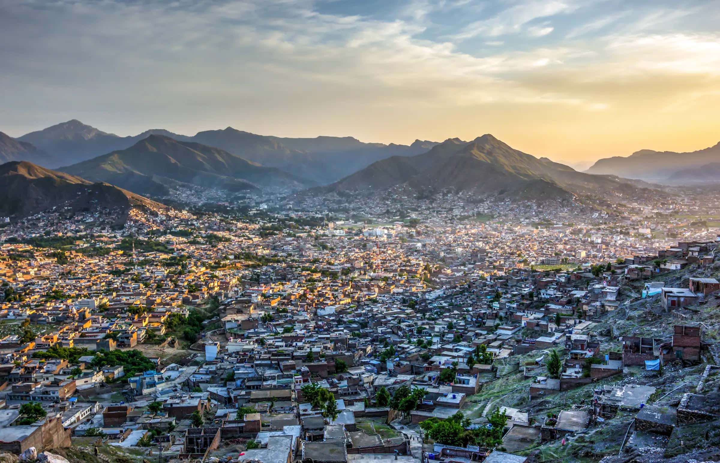 Mingora spread across the Swat valley at sunset, mountains behind it
