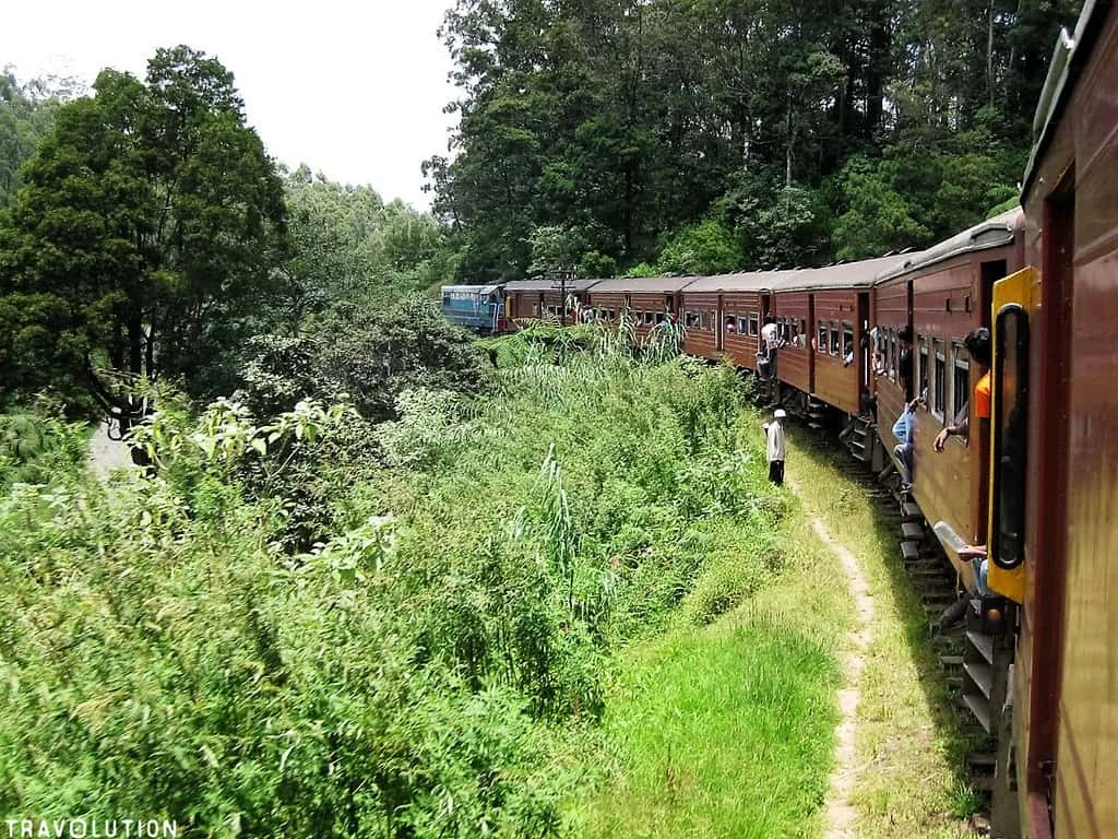 The red hill-country train seen from an open door, winding through the green