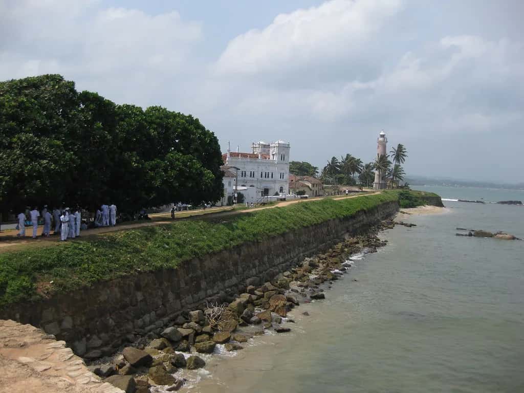 The grass-topped ramparts of Galle fort running out to the sea and the lighthouse