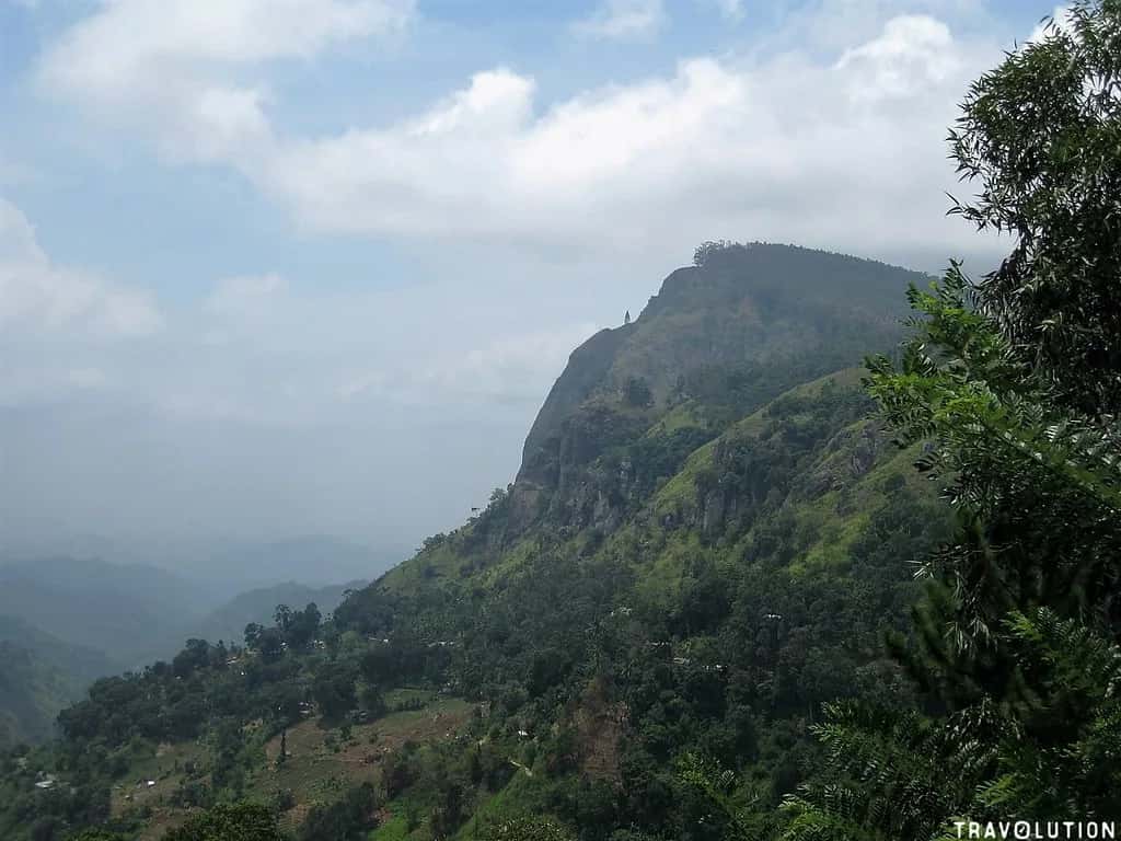 The dark shoulder of Ella Rock above the green hill country under a pale sky