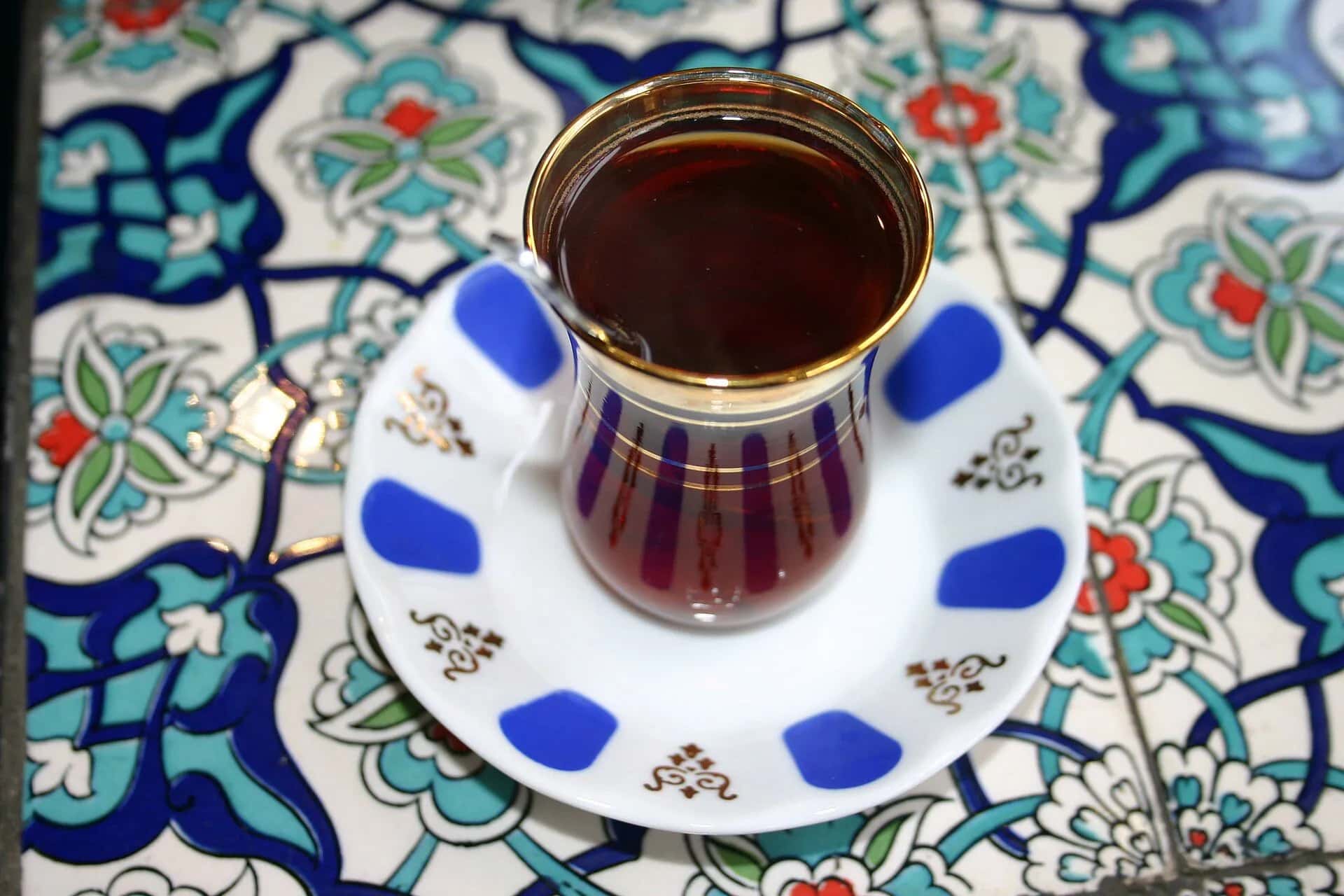 Tea in a tulip glass on a tiled saucer