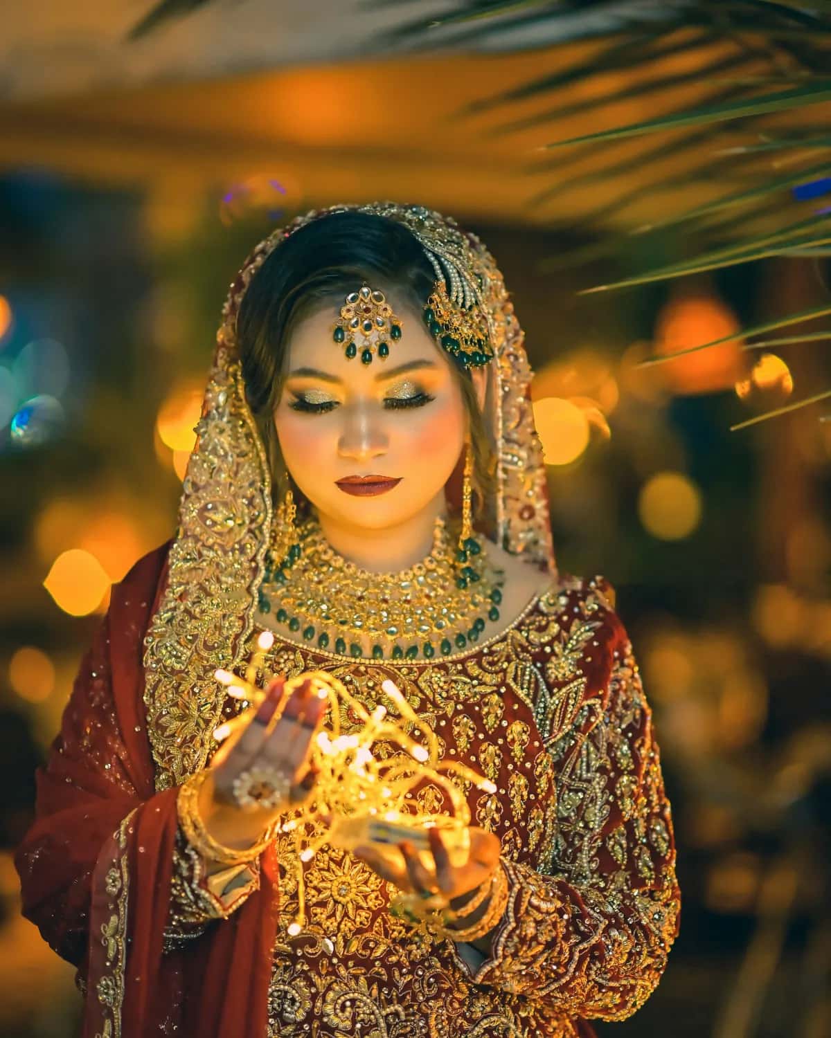 A bride holding a string of fairy lights in her hennaed hands