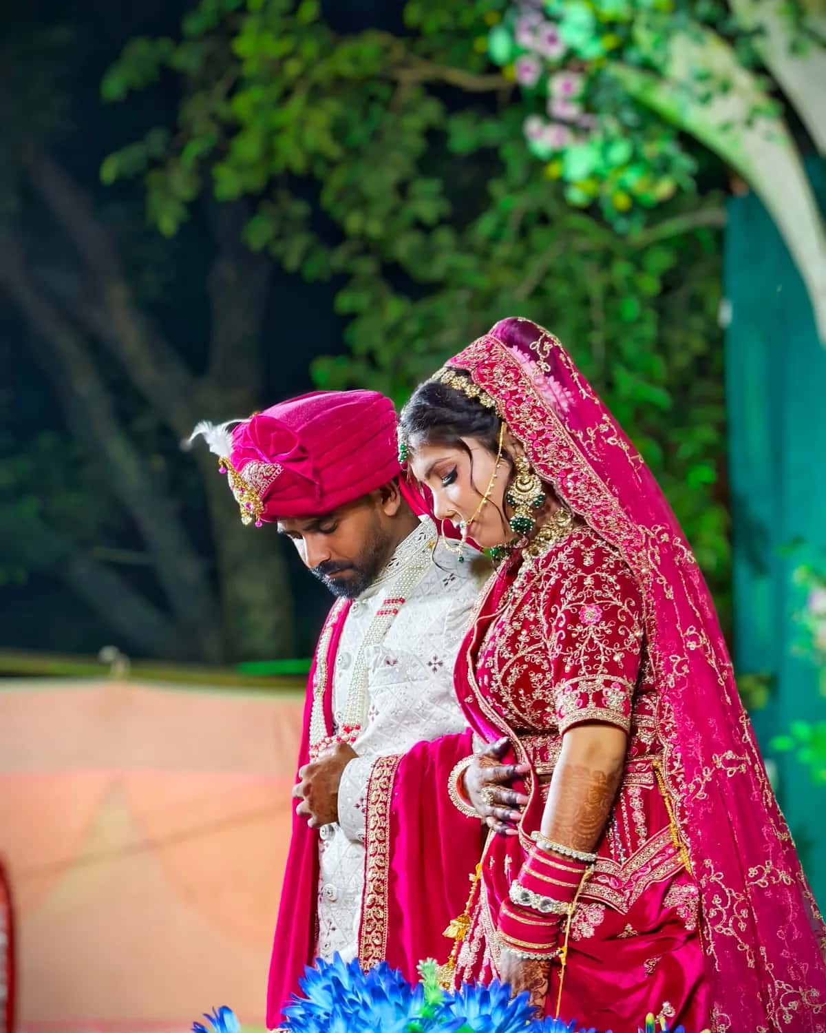 A groom in a pink turban and his bride standing side by side