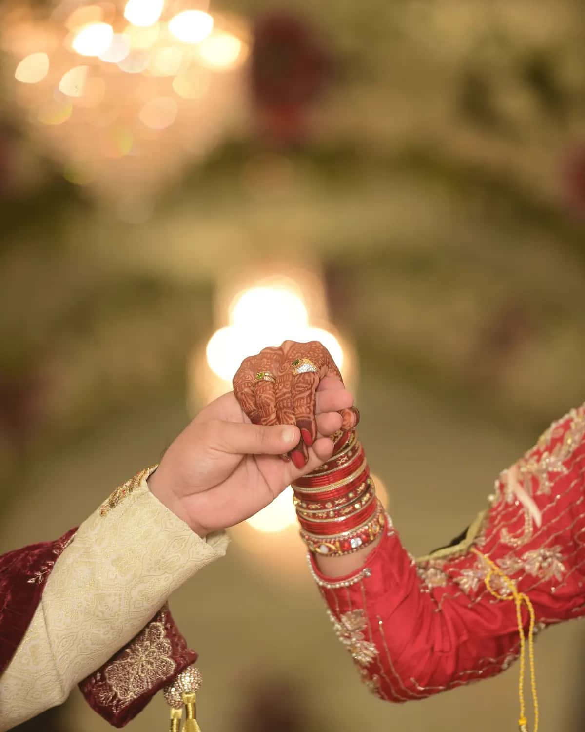 Two hands reaching for each other in the warm light of a decorated hall