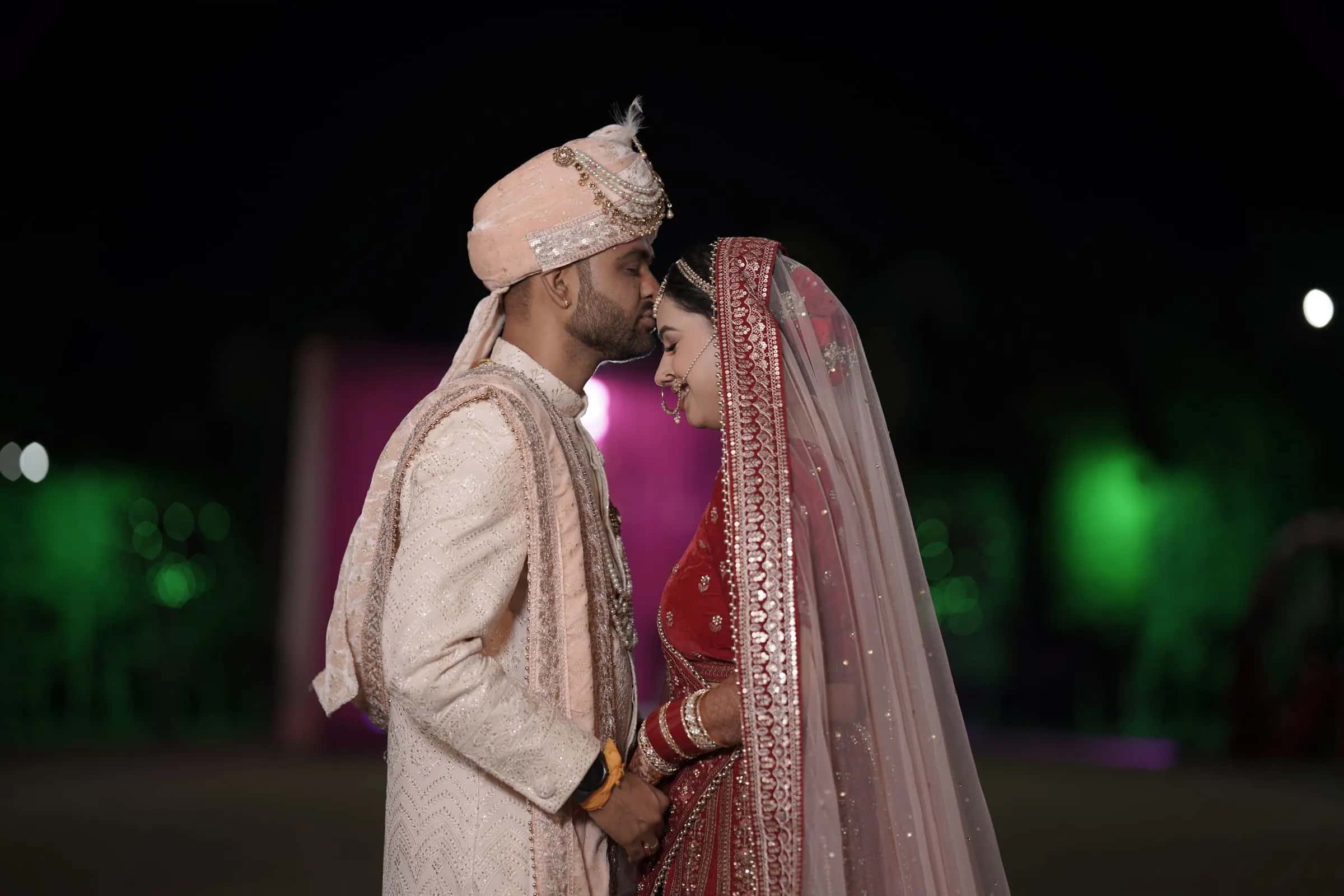 The groom kissing his bride's forehead at night
