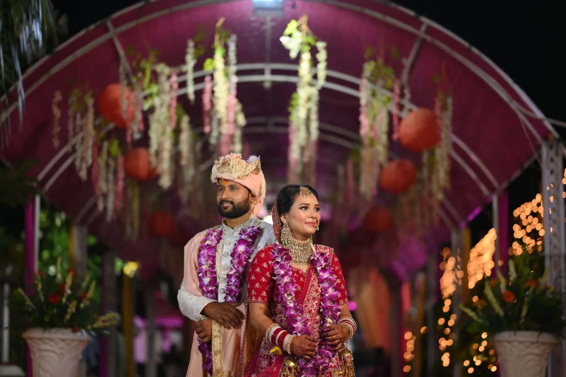 The couple under a floral canopy strung with lights