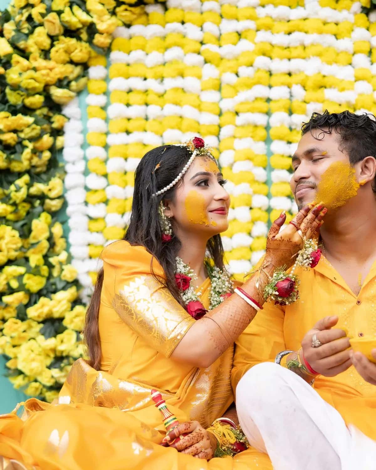 The bride putting turmeric on the groom's cheek at the haldi