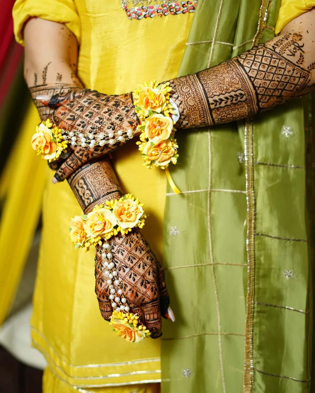 Hennaed hands with flower bracelets on a yellow outfit