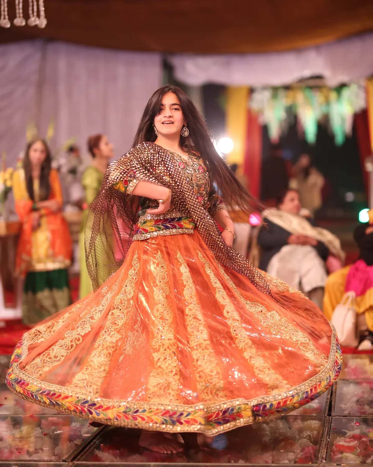 A girl twirling in an orange lehenga at the mehndi
