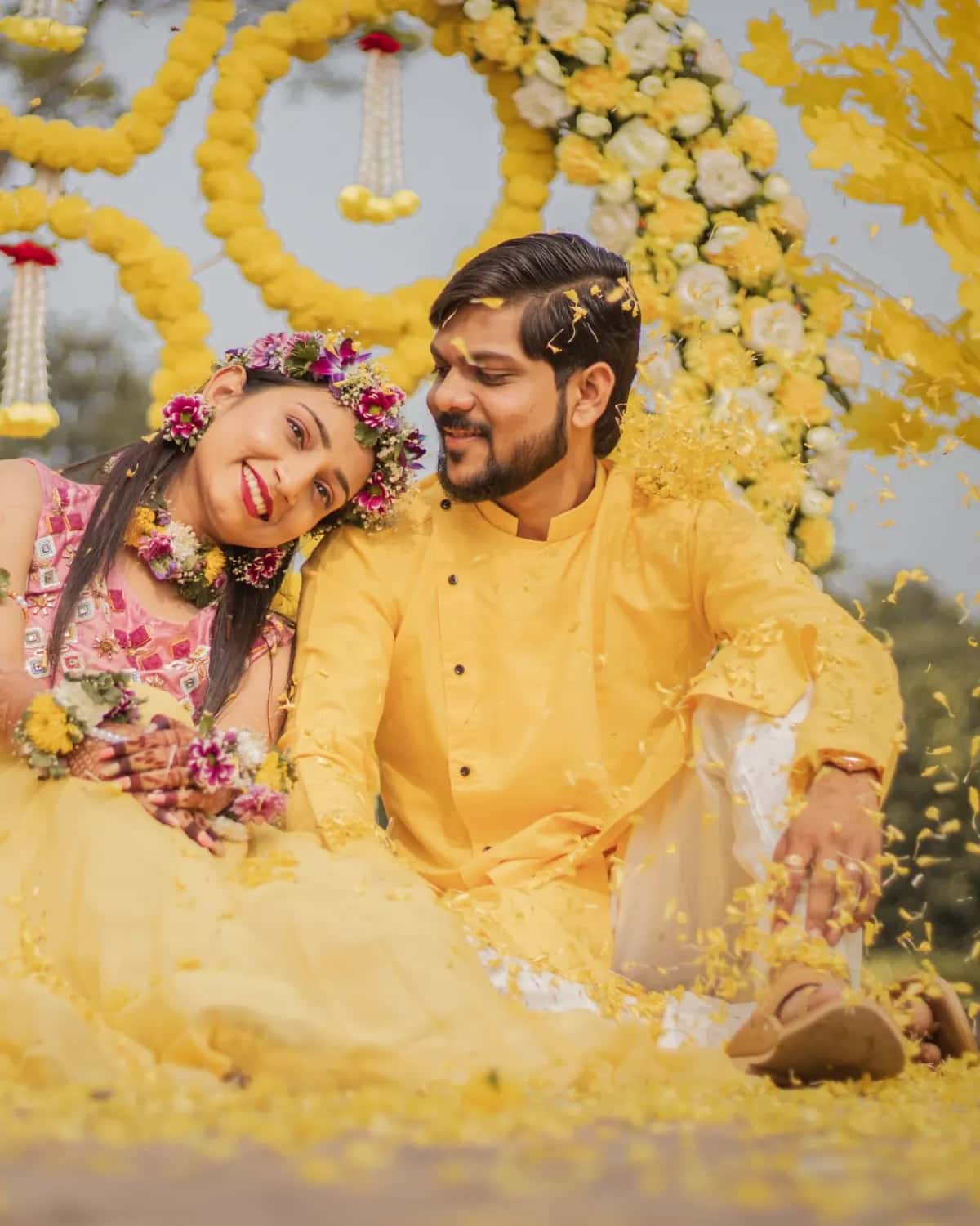 The couple sitting together in a shower of yellow petals