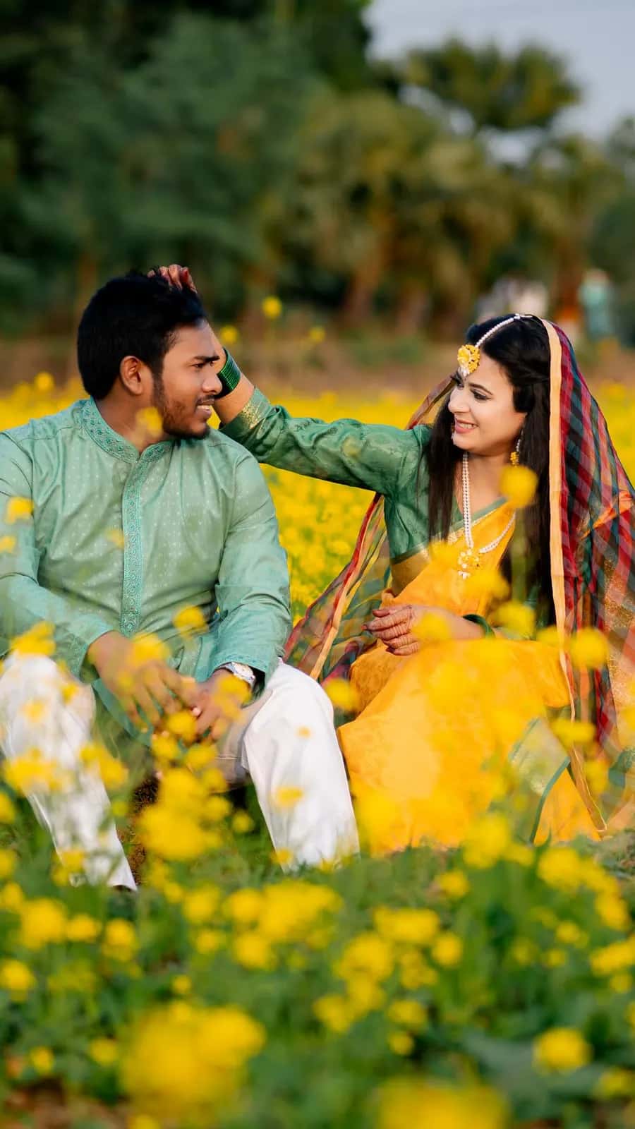 A couple laughing together in a field of yellow flowers