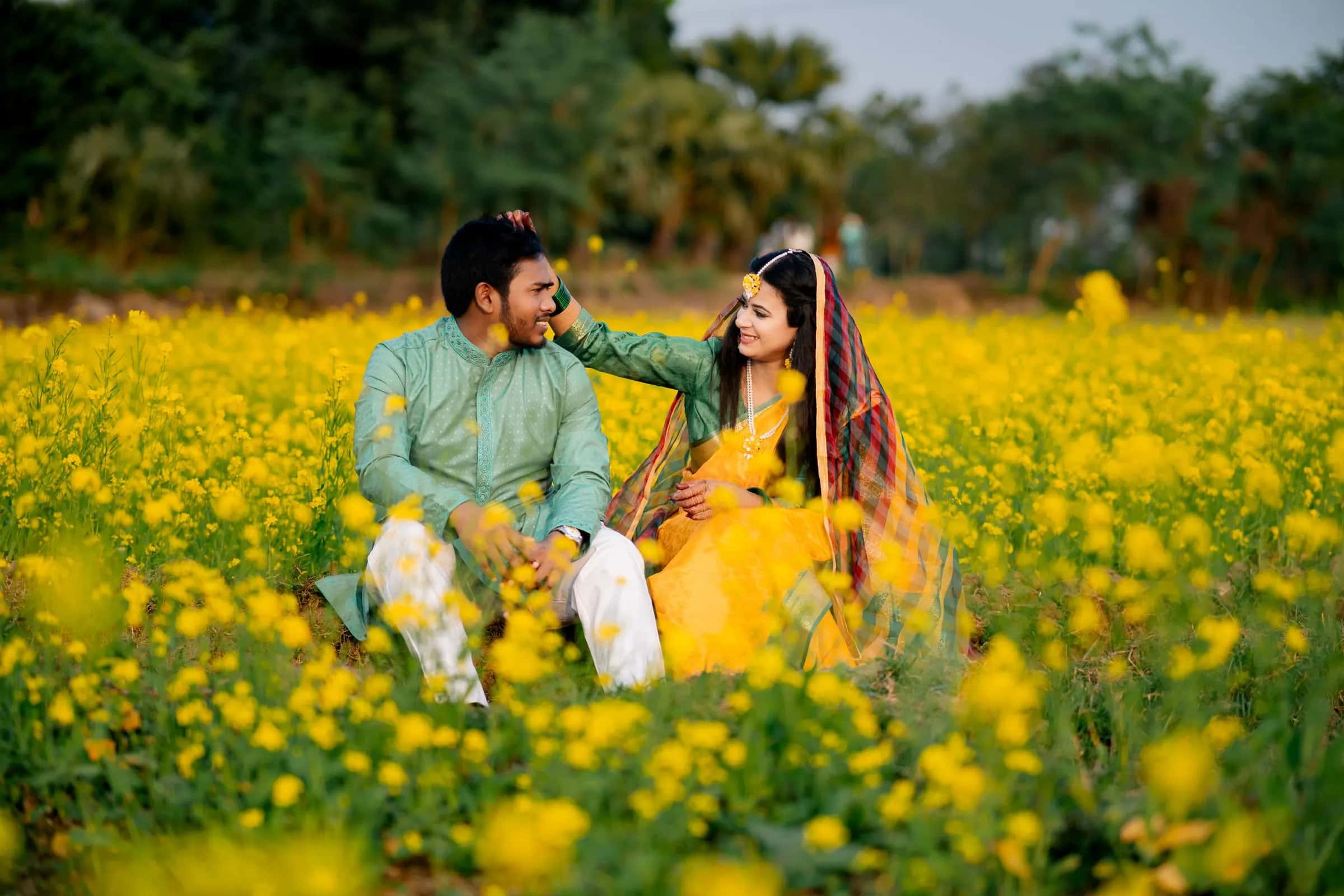 A couple laughing together in a field of yellow flowers