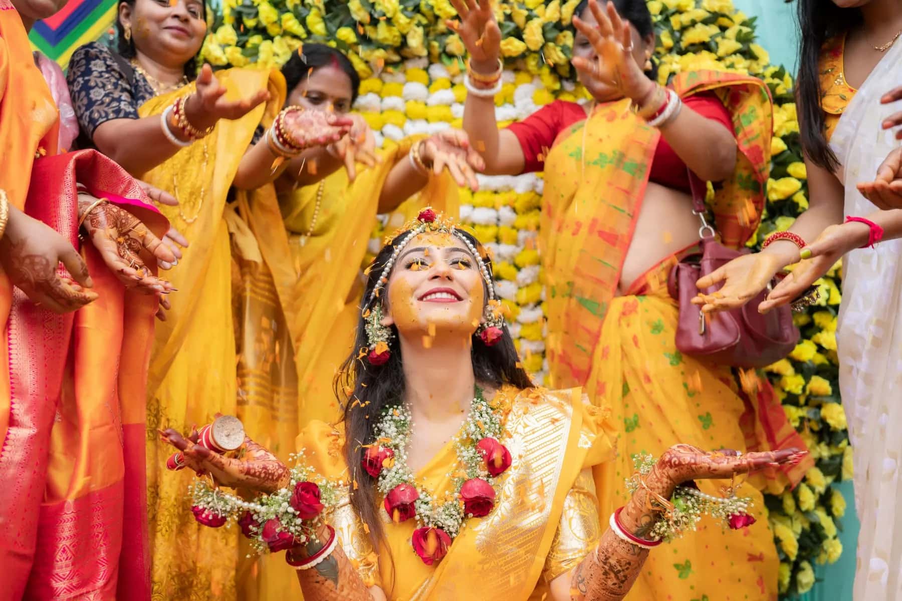 Friends reaching in to put turmeric on the bride