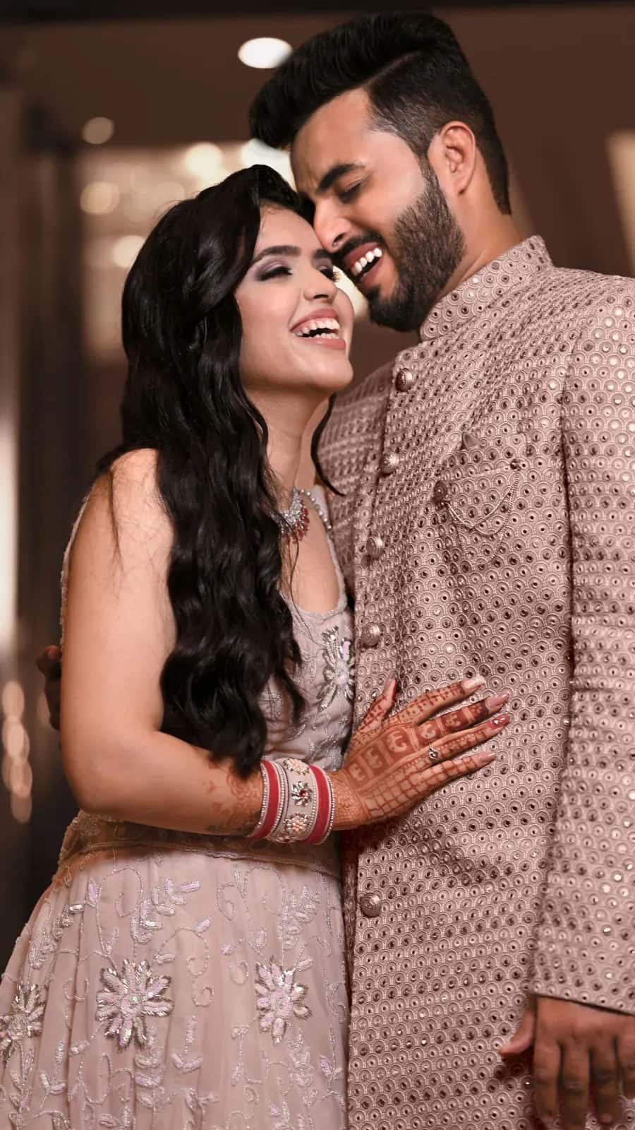 The couple laughing cheek to cheek in blush outfits