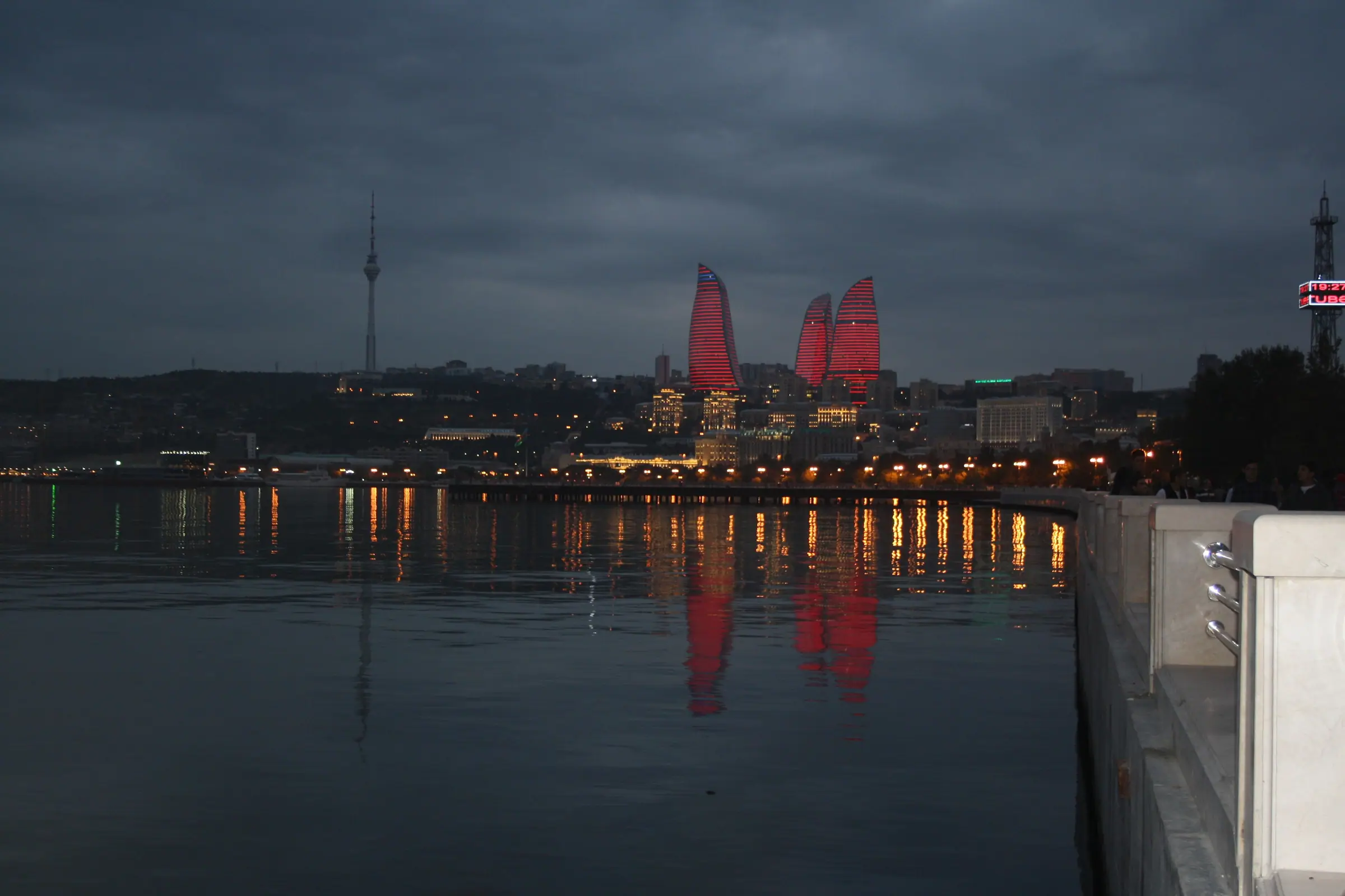 The Flame Towers lit red at dusk above Baku bay, their reflections in the Caspian